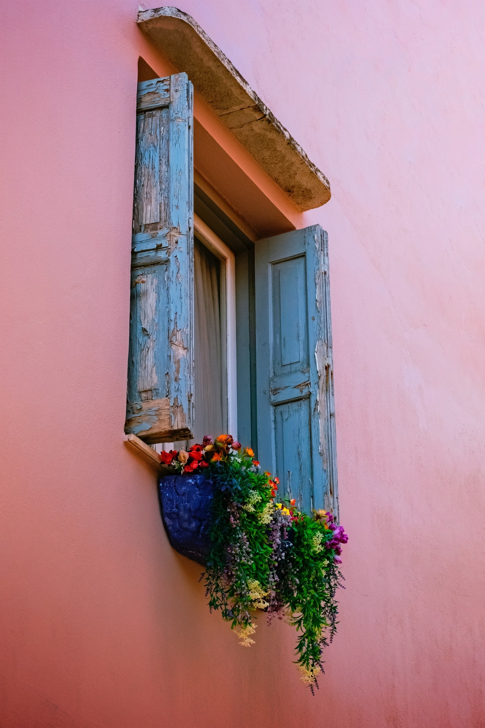 Window with flowers in a peach colored wall in Rethymnon Old Town